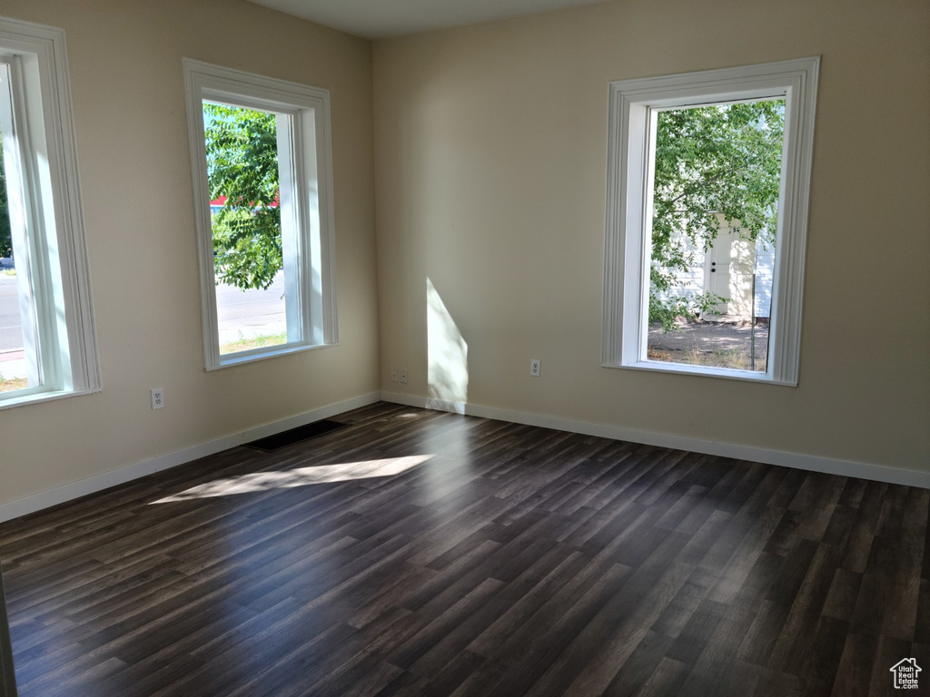 Unfurnished room featuring dark wood-style floors and baseboards