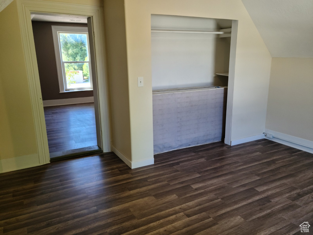 Unfurnished bedroom featuring dark wood finished floors, baseboards, and a closet