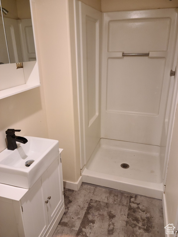 Full bath featuring a shower stall, vanity, and baseboards