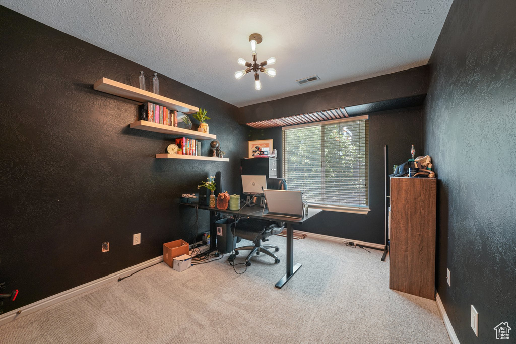 Carpeted office featuring a chandelier, a textured ceiling, and a textured wall