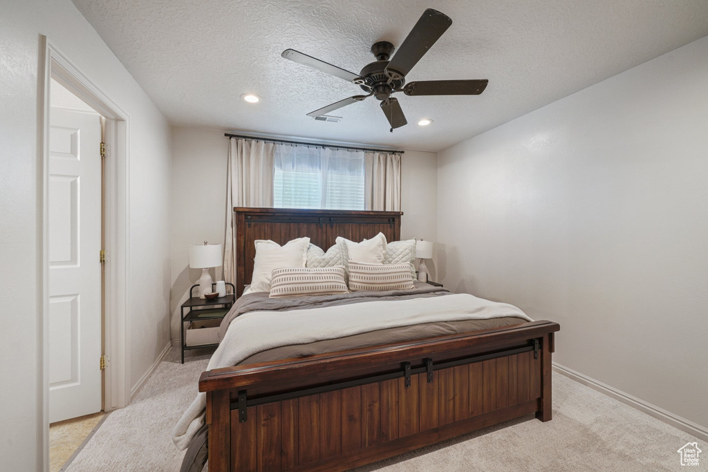 Bedroom with light carpet, recessed lighting, ceiling fan, and a textured ceiling