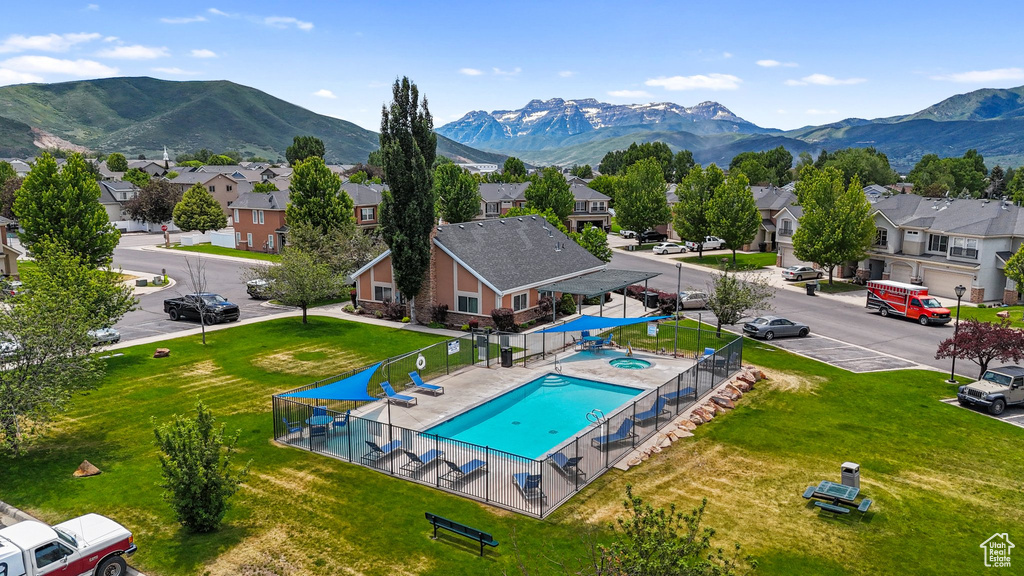 Aerial perspective of suburban area featuring a mountainous background and a pool