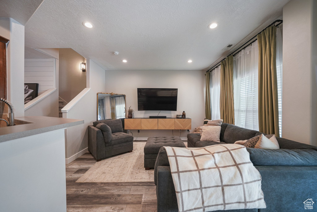 Living room featuring wood finished floors, recessed lighting, a textured ceiling, and stairway