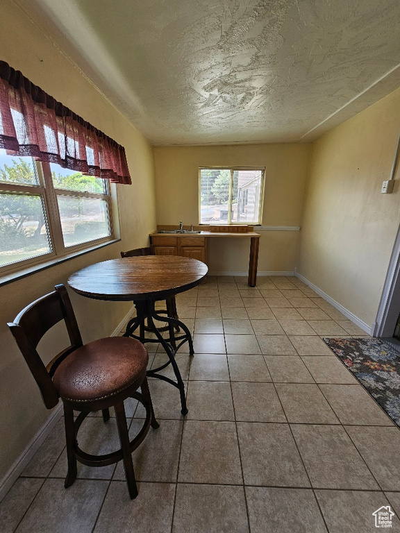 Dining space with plenty of natural light, a textured ceiling, and light tile patterned flooring