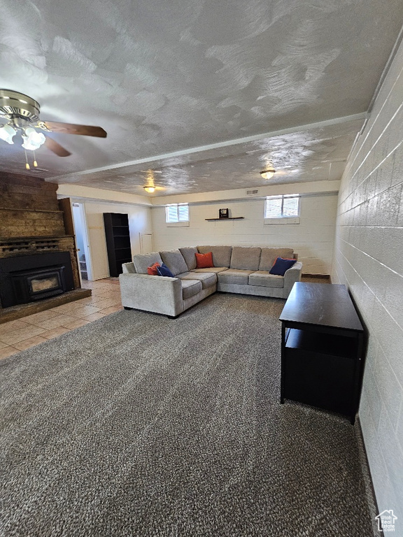 Living room with a fireplace, ceiling fan, concrete block wall, and a textured ceiling