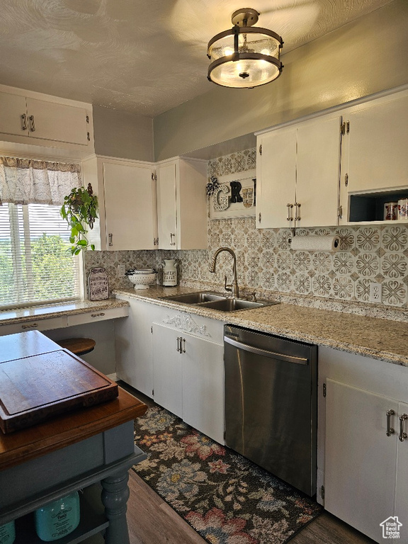 Kitchen featuring stainless steel dishwasher, white cabinetry, and decorative backsplash