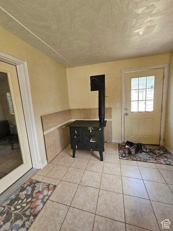 Entryway featuring a wood stove and light tile patterned floors