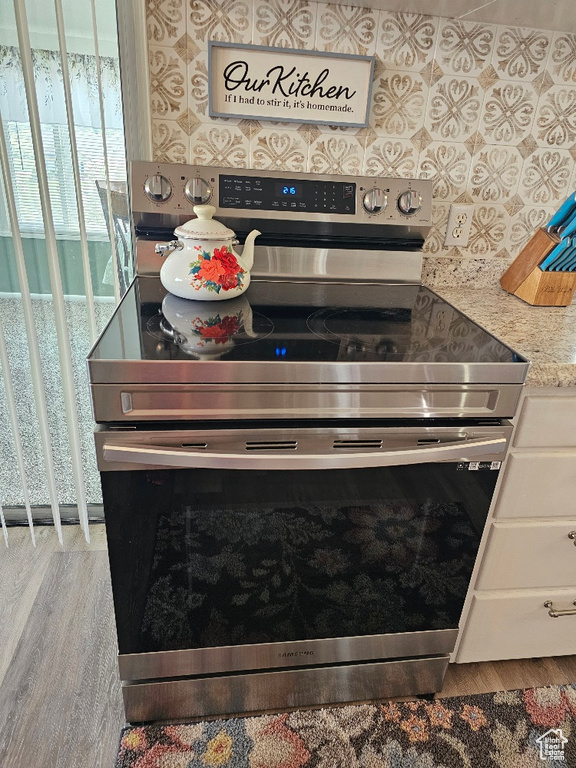 Kitchen view of stainless steel electric range oven and wood finished floors