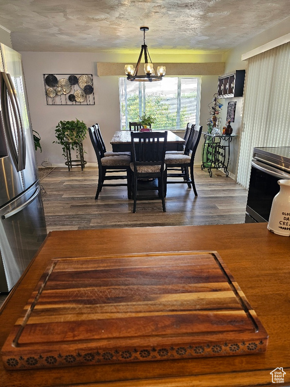 Dining area with dark wood-type flooring, a chandelier, and a textured ceiling