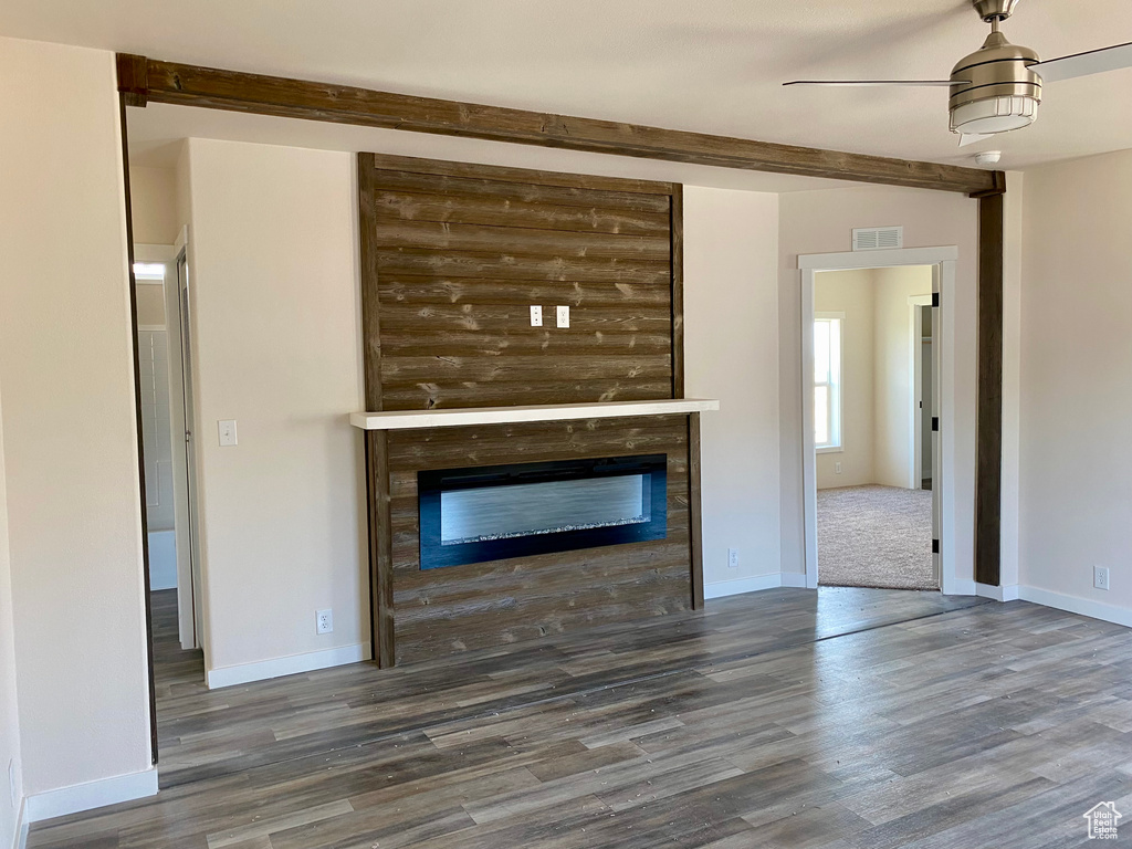 Unfurnished living room featuring wood finished floors, a glass covered fireplace, and ceiling fan