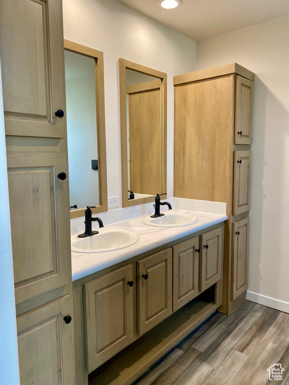 Full bathroom with double vanity, wood finished floors, and recessed lighting