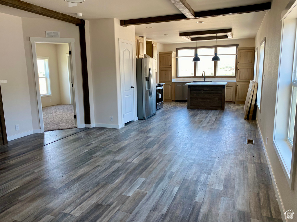 Kitchen featuring stainless steel fridge, beamed ceiling, dark wood-style floors, light countertops, and range