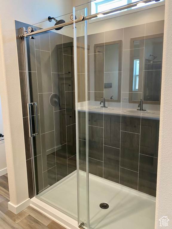 Bathroom featuring a shower stall, wood finished floors, and double vanity
