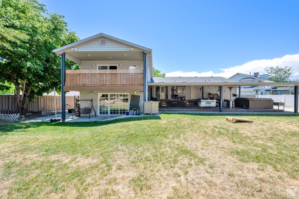 Rear view of house featuring a hot tub, a patio area, and a balcony