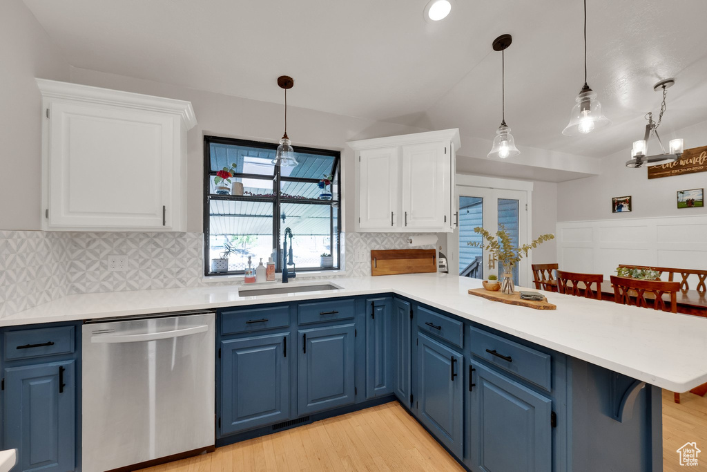 Kitchen with dishwasher, blue cabinetry, a peninsula, tasteful backsplash, and vaulted ceiling