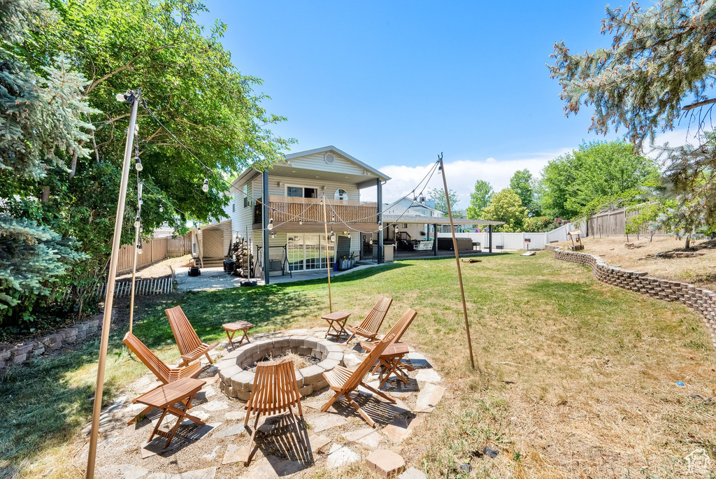 Fenced backyard with an outdoor fire pit, a patio, and a balcony