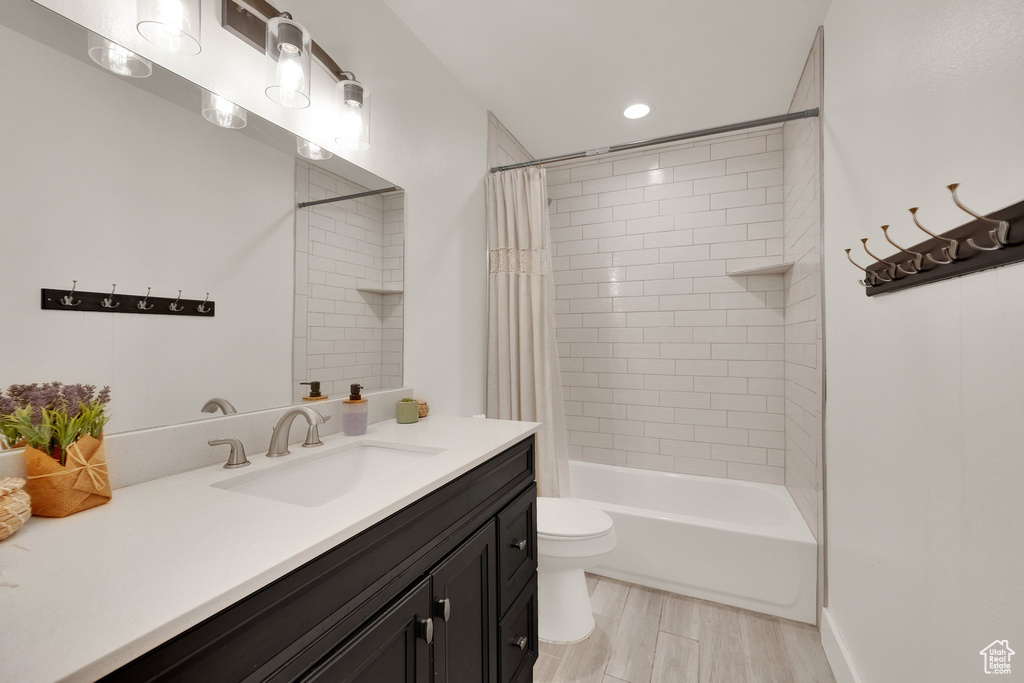 Full bath featuring vanity, shower / bath combo with shower curtain, wood finished floors, and recessed lighting