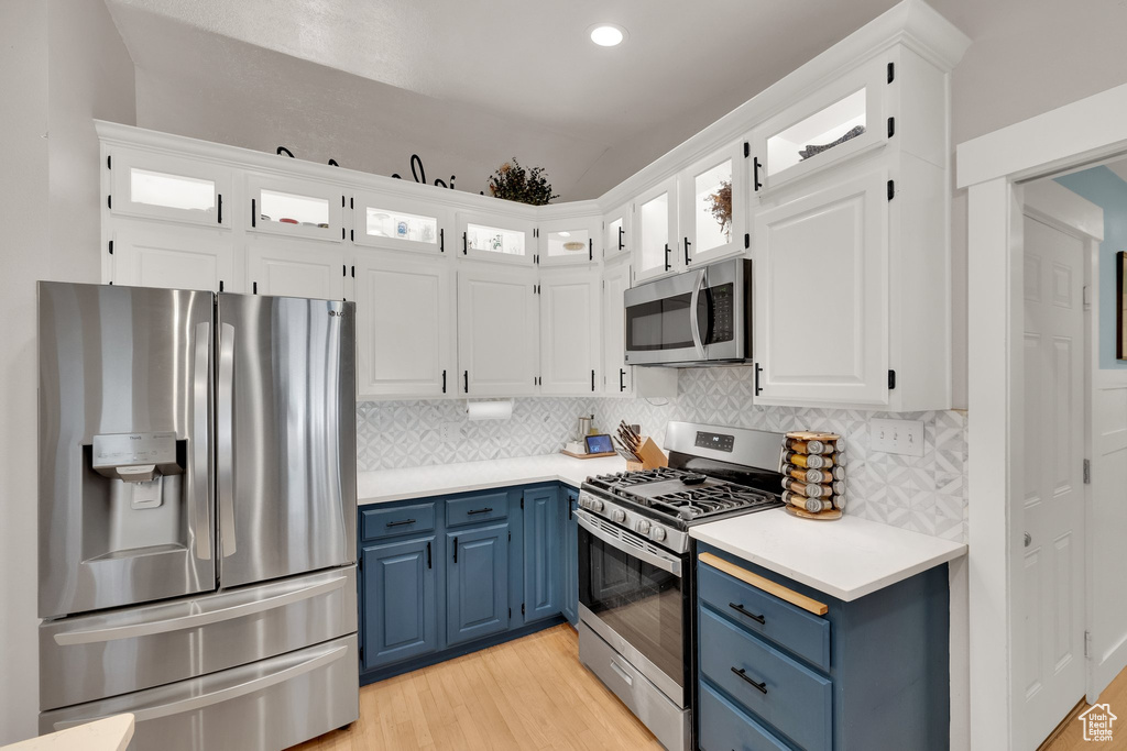 Kitchen featuring appliances with stainless steel finishes, blue cabinets, light wood-type flooring, light countertops, and recessed lighting