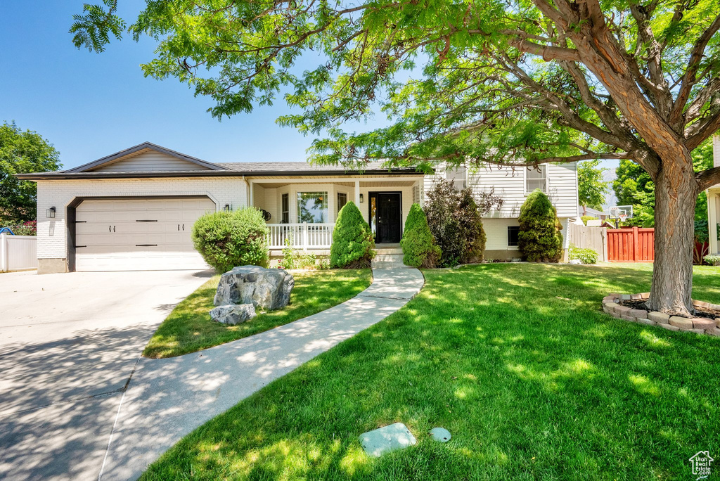 Ranch-style home featuring covered porch, an attached garage, concrete driveway, and brick siding