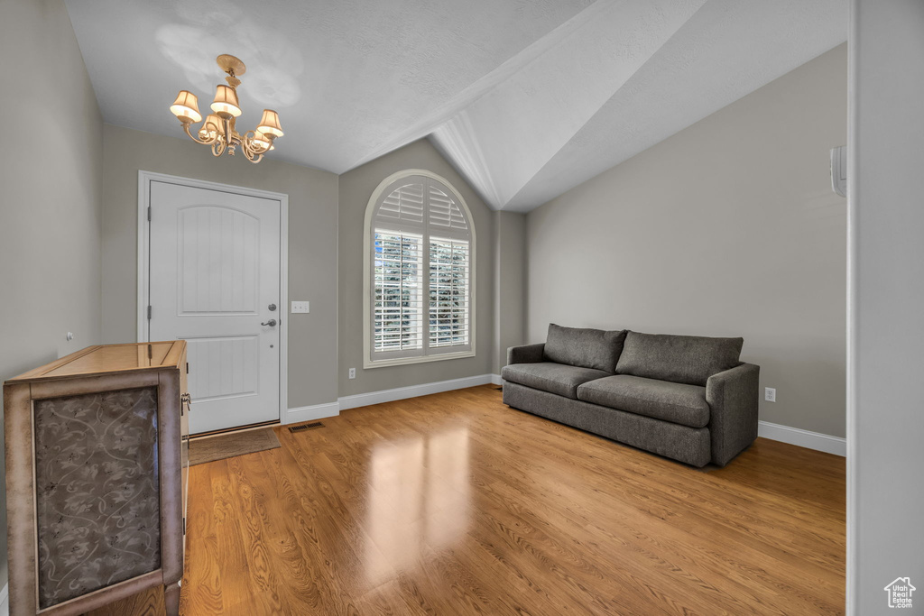 Foyer featuring a chandelier, wood finished floors, and vaulted ceiling