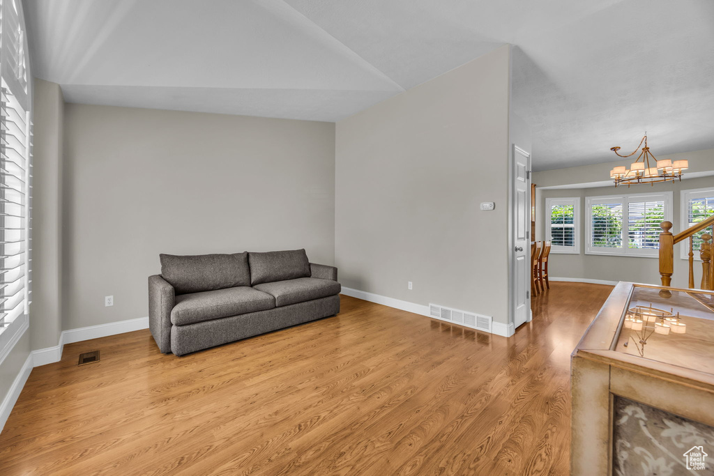 Living area with a chandelier, wood finished floors, and lofted ceiling