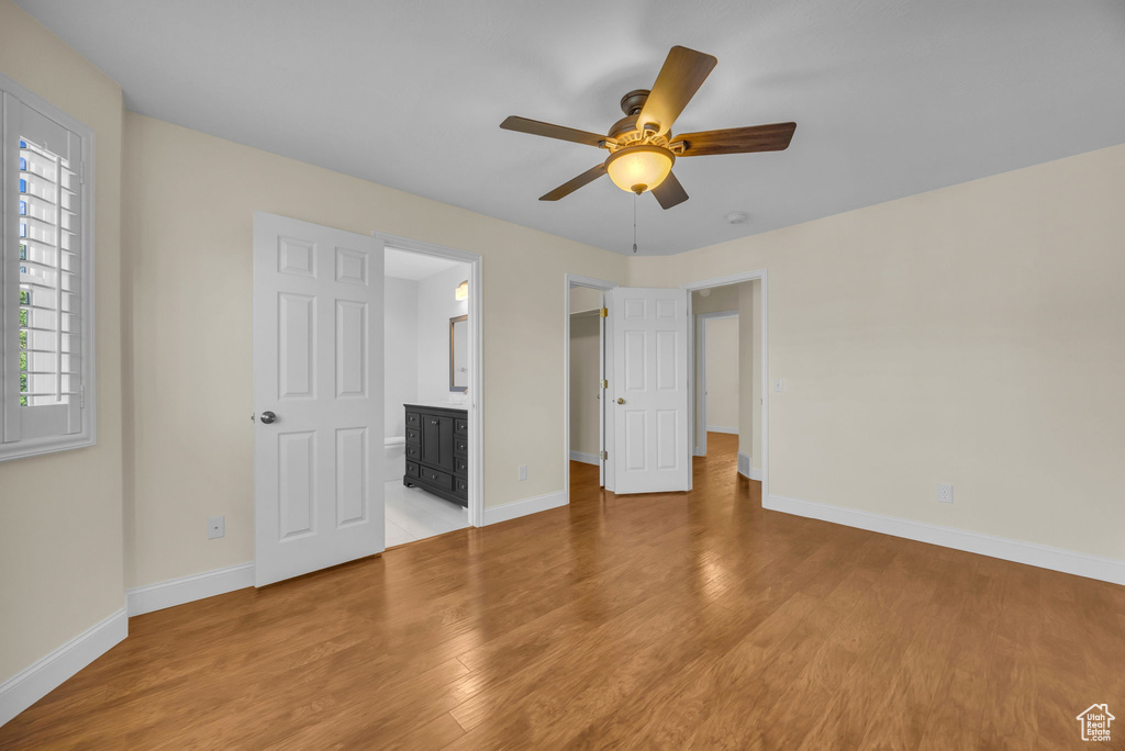 Unfurnished bedroom with light wood-style floors, connected bathroom, and ceiling fan