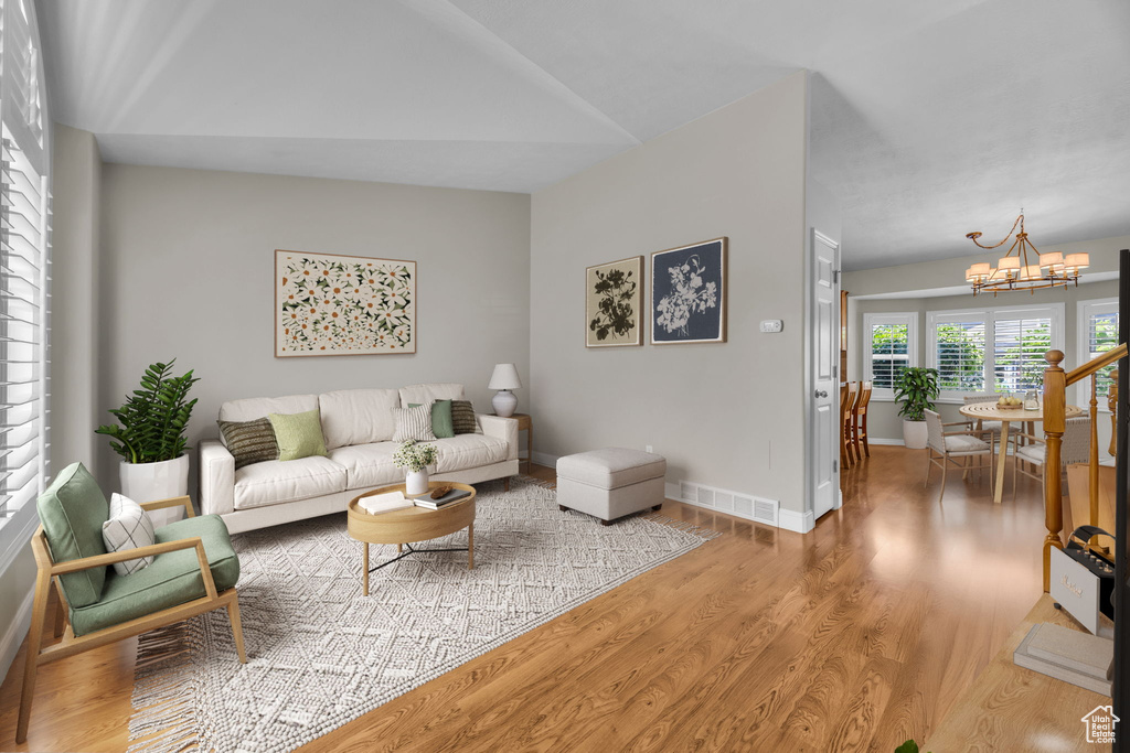 Living area featuring a chandelier, light wood-type flooring, and vaulted ceiling