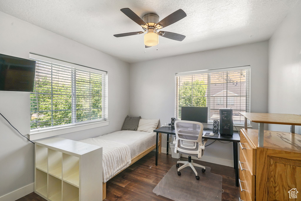 Bedroom featuring dark wood-style floors, a desk, a ceiling fan, and a textured ceiling