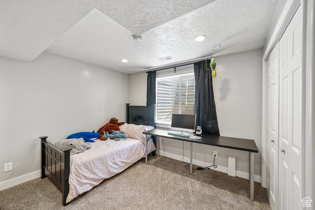 Bedroom with carpet, a textured ceiling, a desk, recessed lighting, and a closet