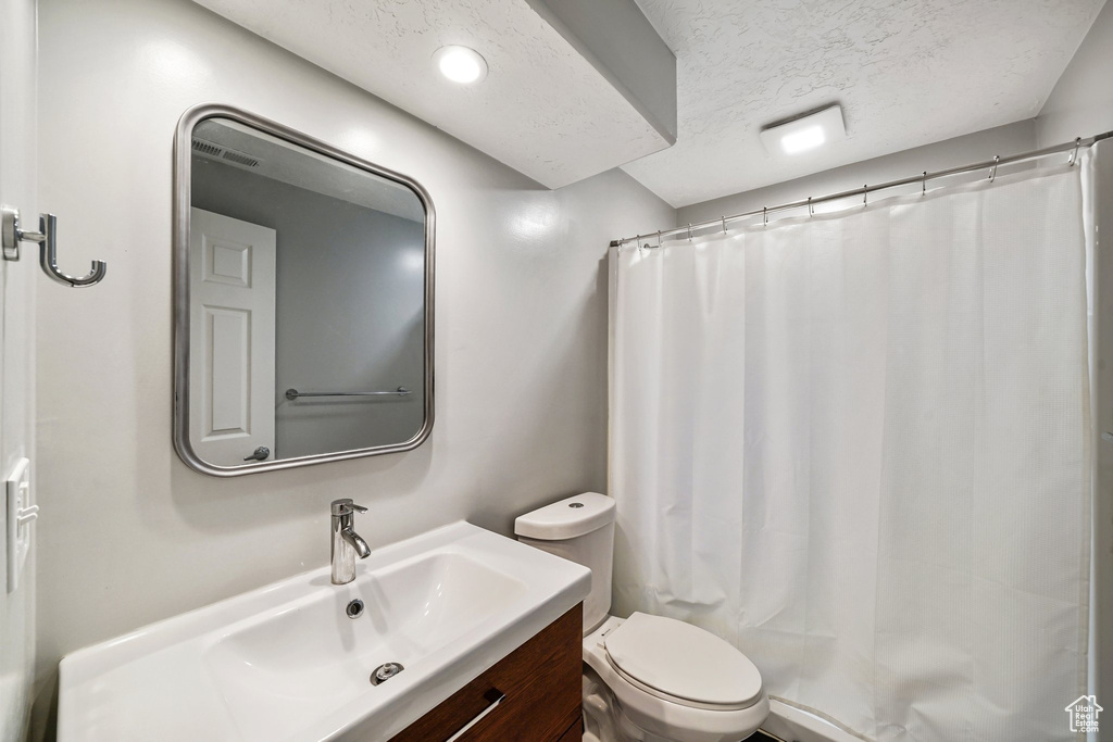 Bathroom with vanity, a textured ceiling, and a shower with shower curtain