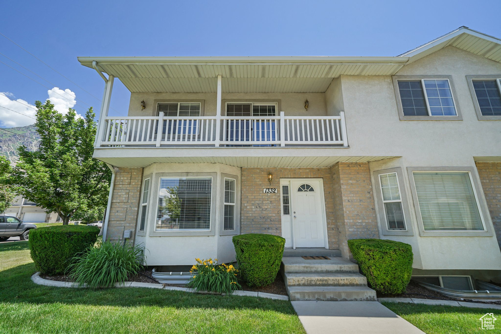 Multi unit property featuring a balcony, stucco siding, and brick siding