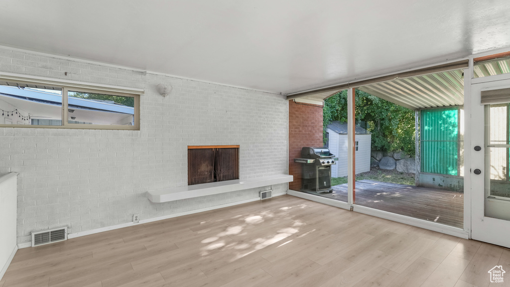 Unfurnished living room with wood finished floors, a fireplace, and healthy amount of natural light