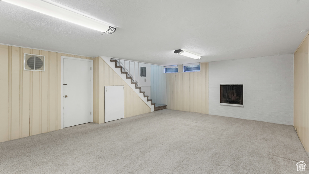 Finished below grade area with carpet floors, stairway, and a brick fireplace