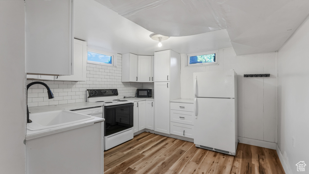 Kitchen featuring freestanding refrigerator, black microwave, a sink, range with electric stovetop, and white cabinetry