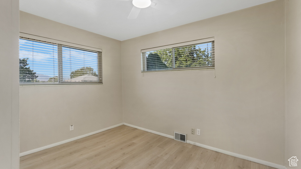 Unfurnished room featuring light wood finished floors, a ceiling fan, and baseboards