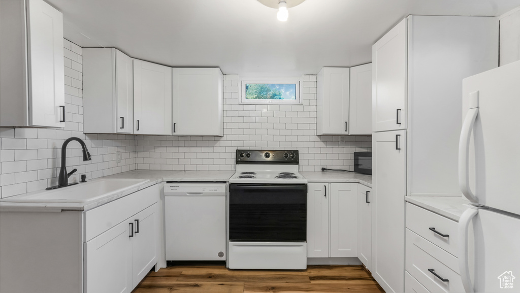 Kitchen featuring white appliances, light countertops, tasteful backsplash, and white cabinetry
