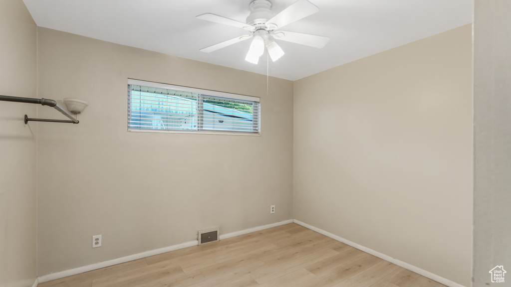 Empty room featuring light wood-type flooring, baseboards, and a ceiling fan