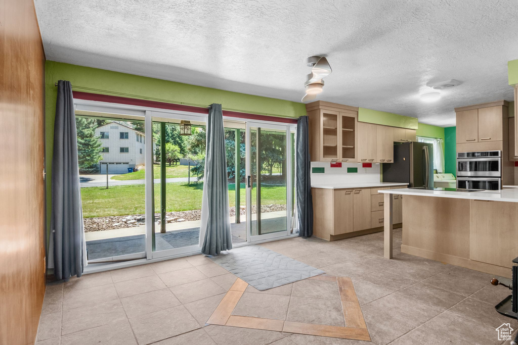 Kitchen featuring stainless steel double oven, light countertops, plenty of natural light, a textured ceiling, and light tile patterned flooring