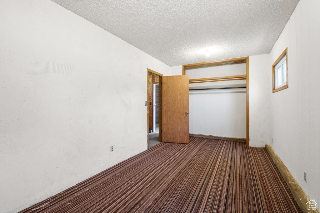Unfurnished bedroom featuring a textured ceiling, carpet floors, and a closet