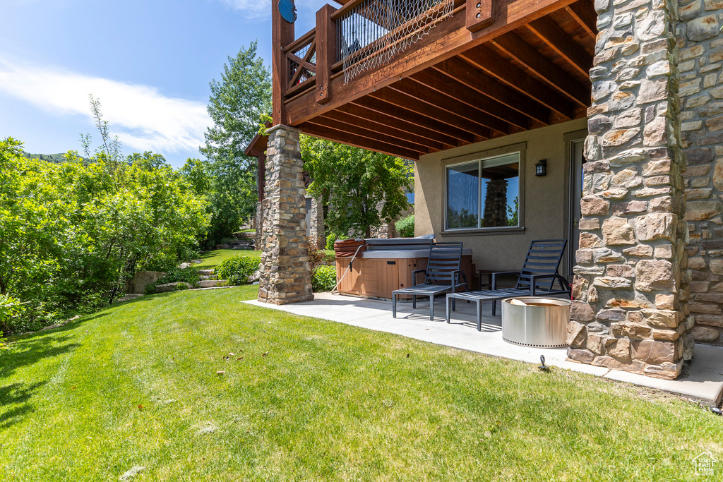View of green lawn with a hot tub, a patio area, and a deck
