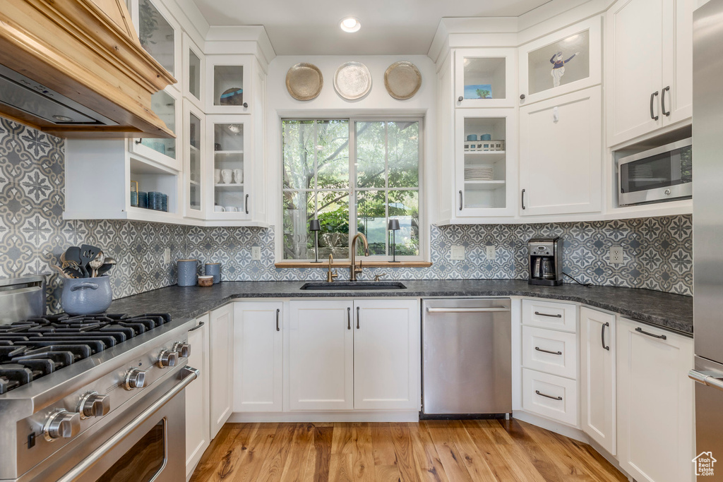 Kitchen featuring stainless steel appliances, premium range hood, and white cabinets