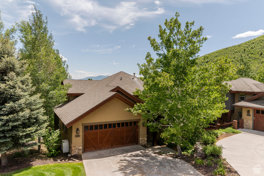 View of front of home featuring stone siding, concrete driveway, a garage, and stucco siding