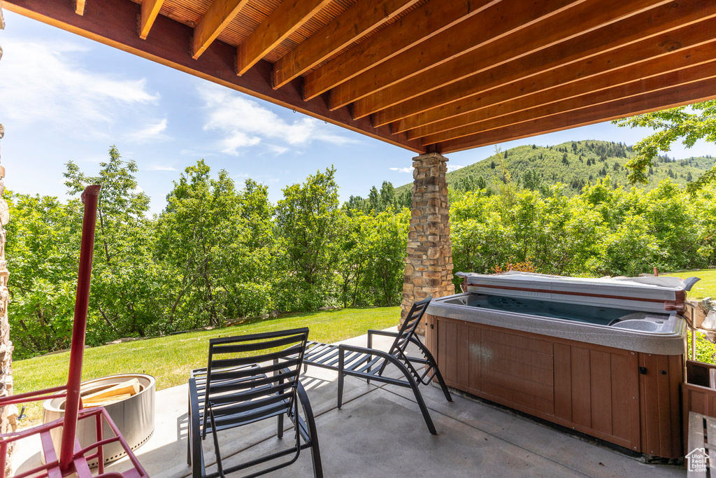 View of patio featuring a hot tub and a view of trees