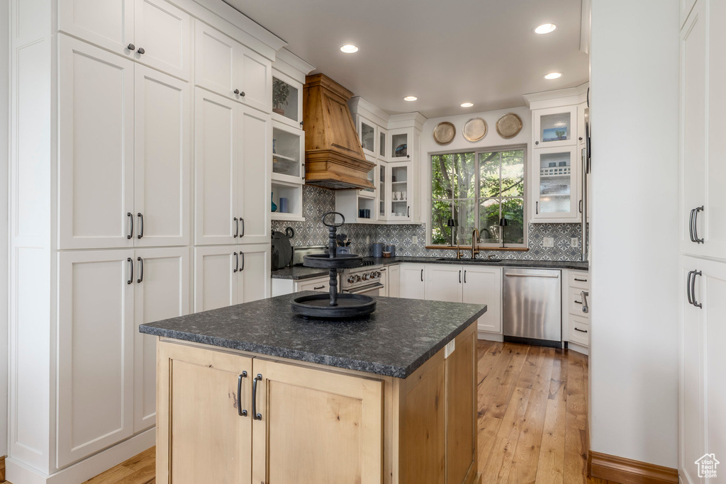 Kitchen featuring appliances with stainless steel finishes, backsplash, light wood-type flooring, recessed lighting, and custom exhaust hood