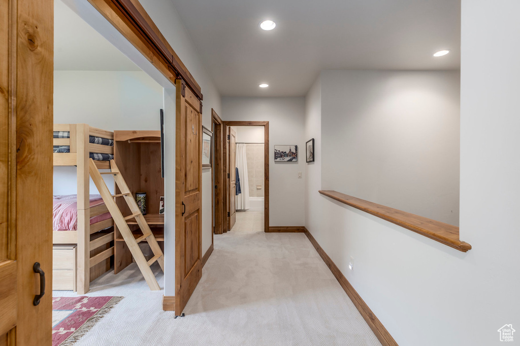 Hallway with light colored carpet, recessed lighting, and a barn door