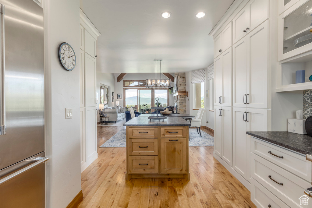 Kitchen with high quality fridge, light wood-style floors, a kitchen island, a chandelier, and recessed lighting