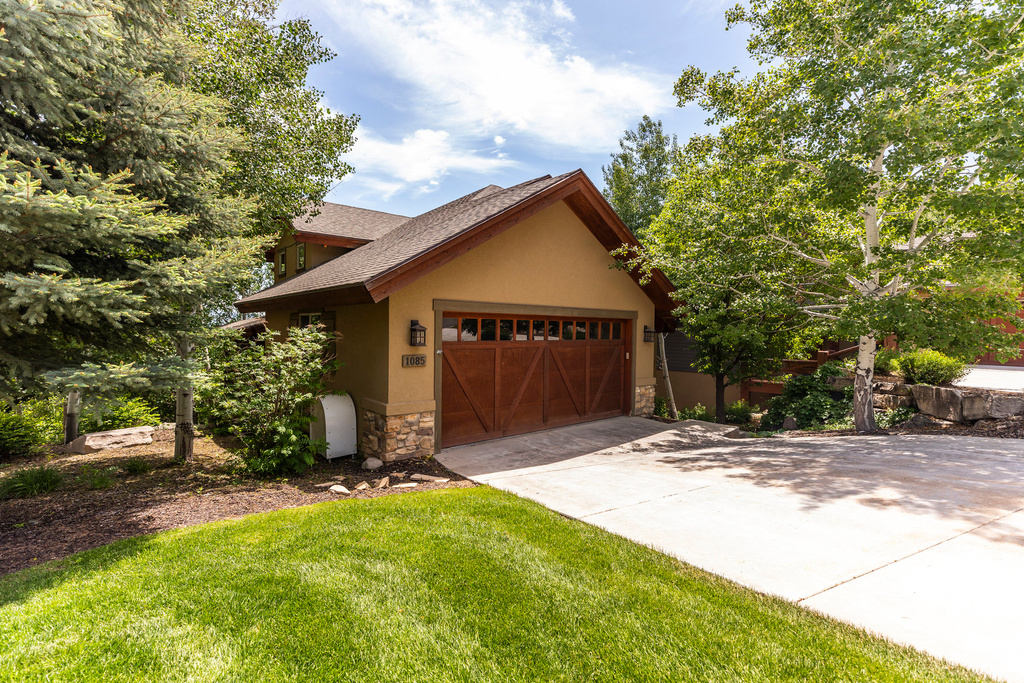 View of front facade with stone siding, stucco siding, a garage, concrete driveway, and a front lawn
