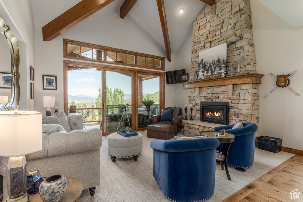 Living room with beamed ceiling, high vaulted ceiling, a fireplace, and wood finished floors