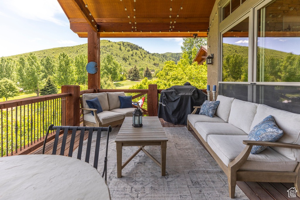 Wooden terrace with outdoor lounge area, a grill, a forest view, and a mountain view