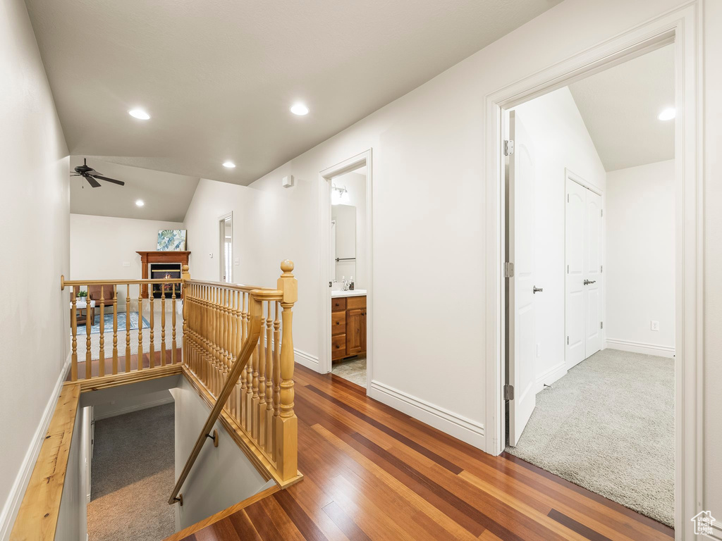 Hallway featuring an upstairs landing, vaulted ceiling, recessed lighting, and wood finished floors